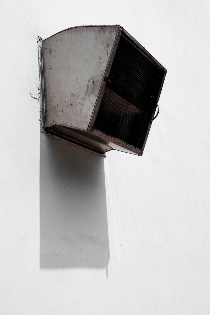 A minimalist ventilator casting dramatic shadows on a white wall in urban Taipei.
